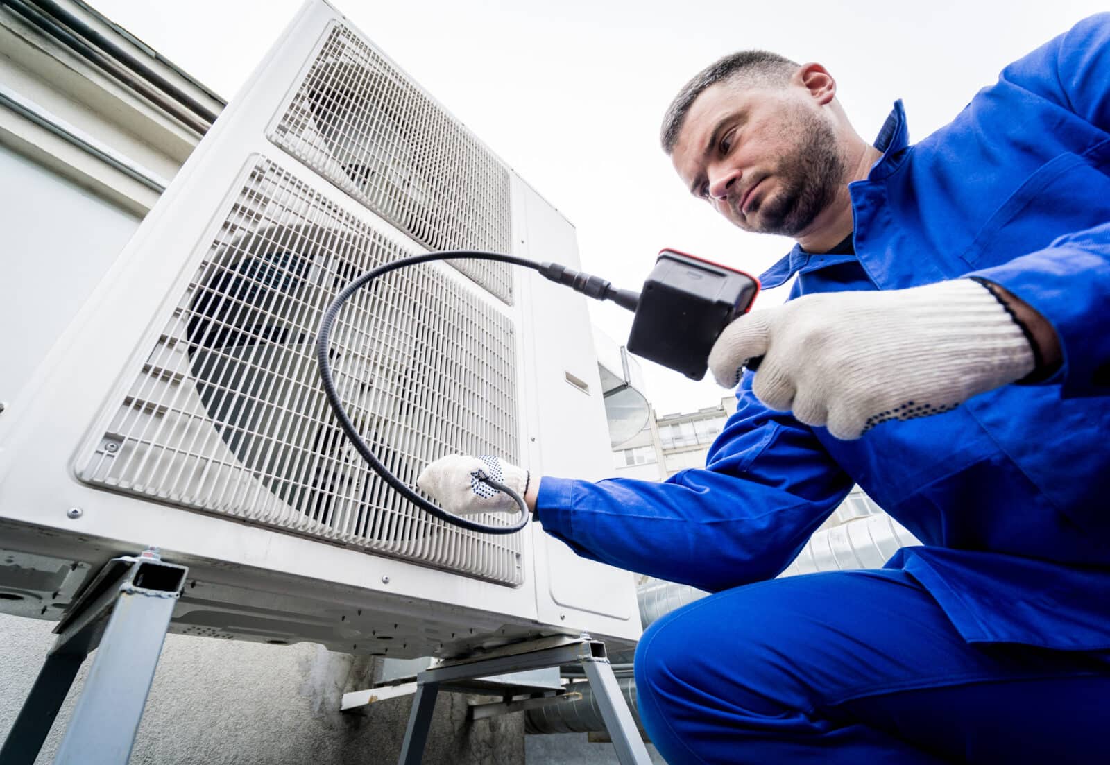 Engineer servicing outdoor heat pump unit