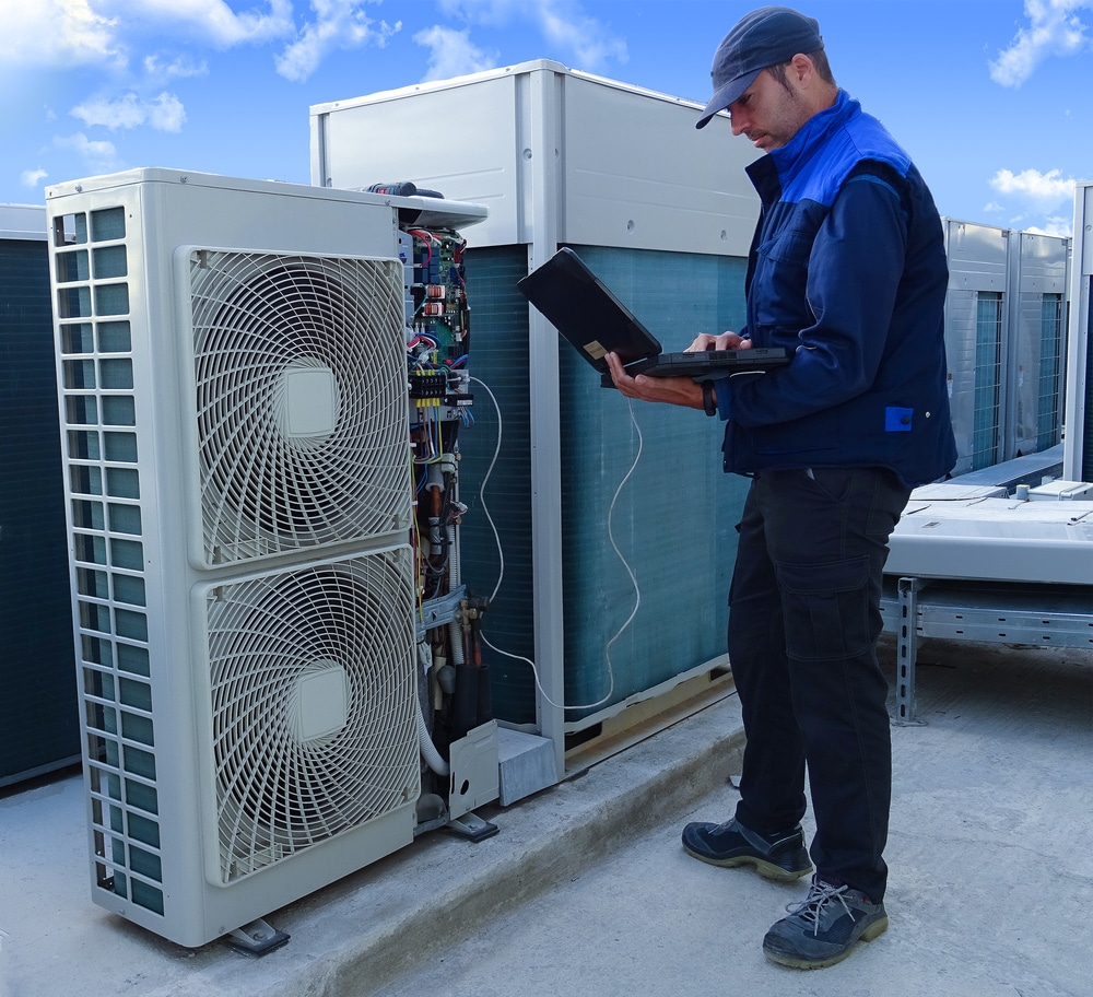 Air conditioning technician diagnosing rooftop HVAC unit